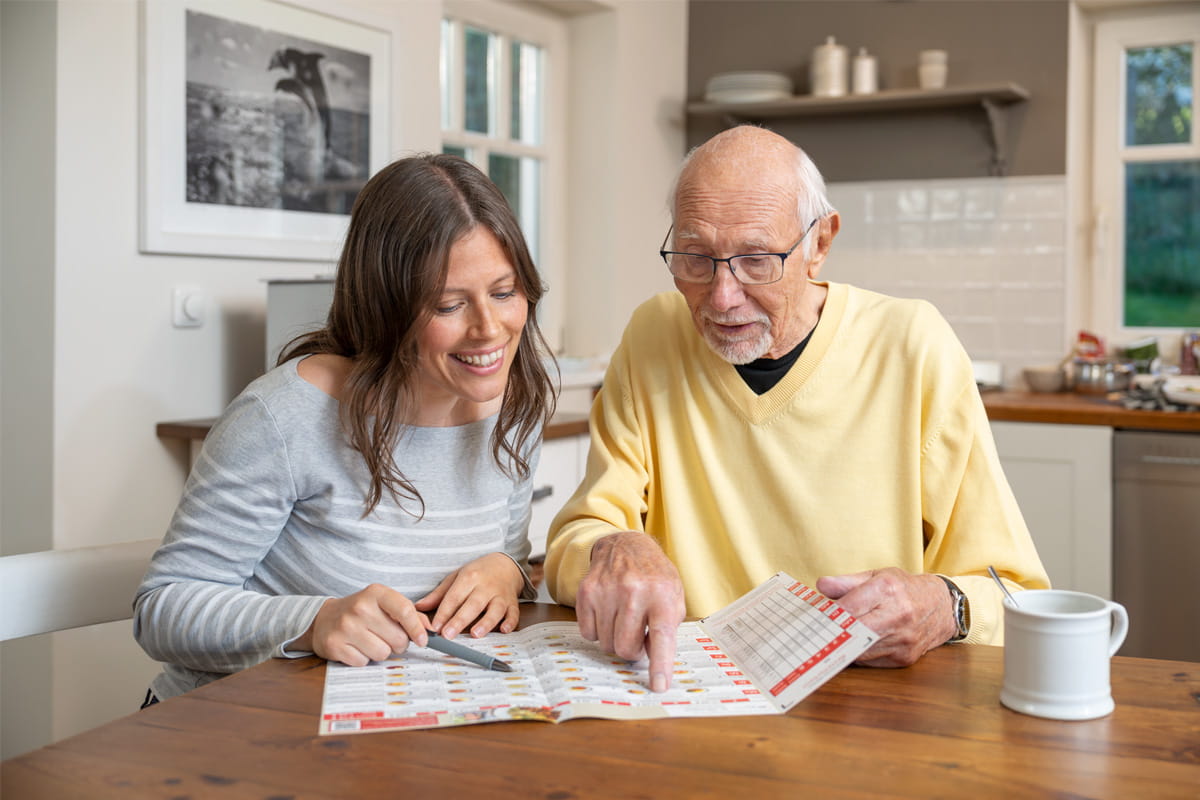 Junge Dame und alter Herr blättern freudig in Zeitschrift