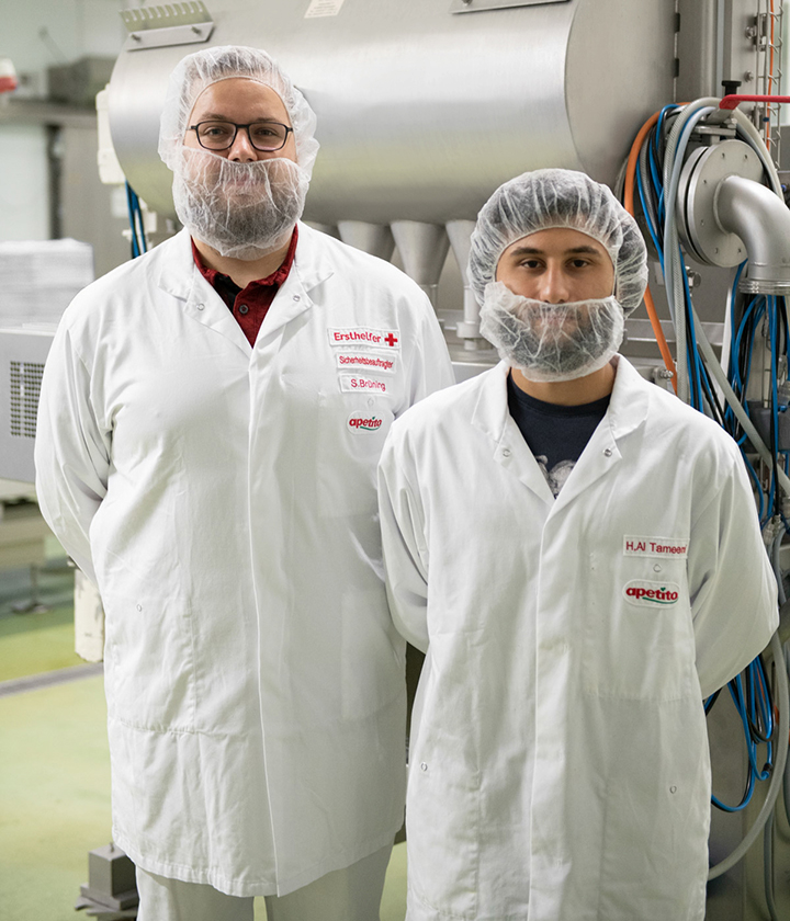 Zwei-Mitarbeitende-von-apetito-mit-Kochkleidung-in-der-Produktion