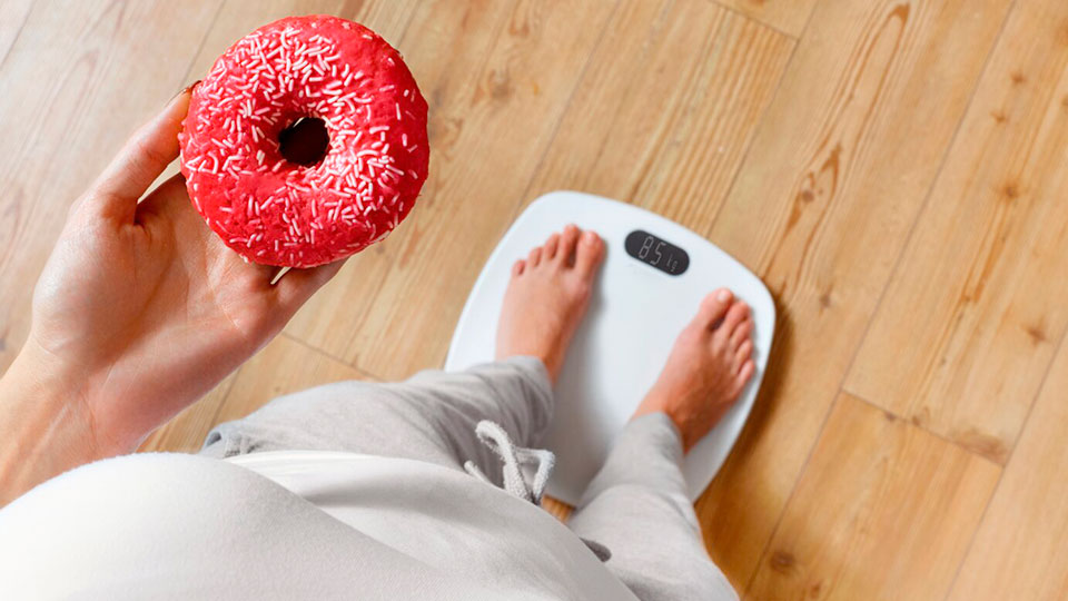 Frau-auf-Waage-mit-Donut-in-der-Hand