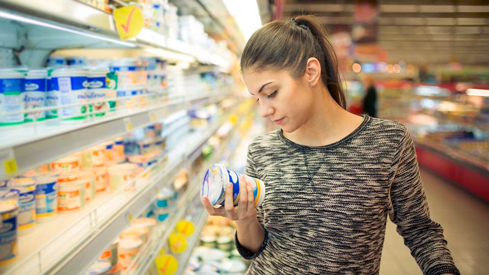 apetito-Magazin_Frau guckt sich das Etikett eines Joghurts an im Supermarkt