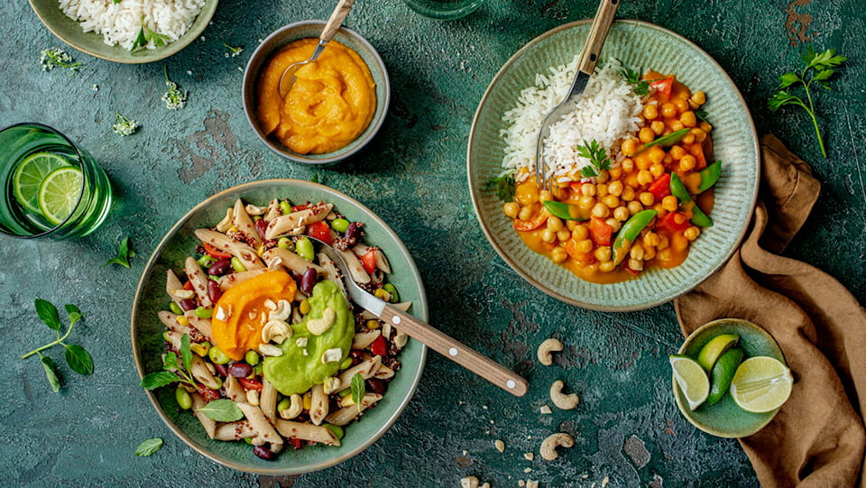 Schuessel-mit-Kichererbsencurry-und-Schuessel-mit-Proteinbowl-schoen-angerichtet-auf-einem-Tisch