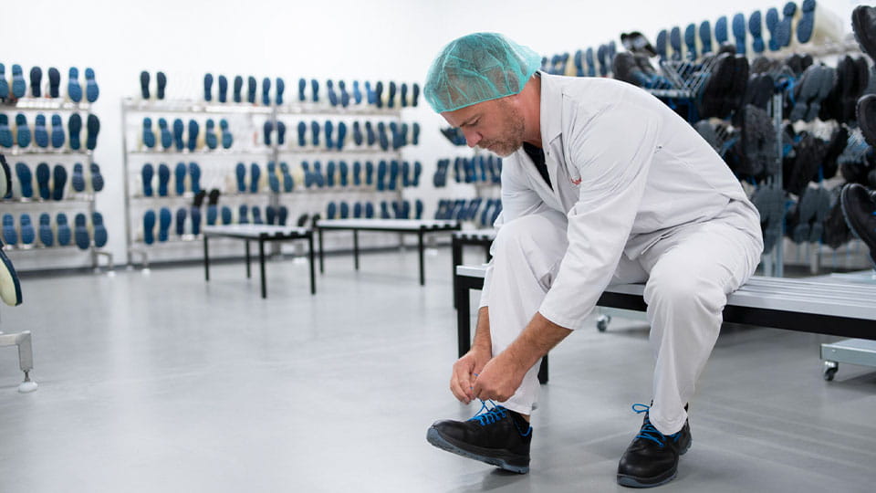 Mitarbeiter zieht Sicherheitsschuhe an - Arbeitssicherheit und Gesundheitsschutz