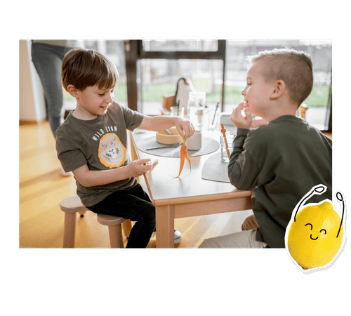 Zwei Kita-Kinder spielen mit einer Möhre