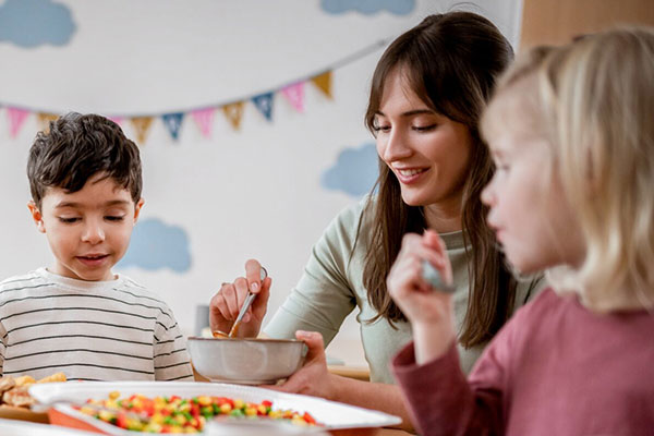 Kinder_am_Tisch_mit_Erzieherin-Schulung